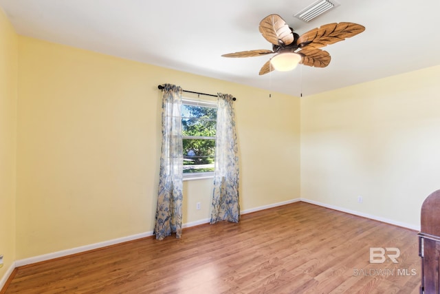 empty room featuring baseboards, wood finished floors, visible vents, and a ceiling fan