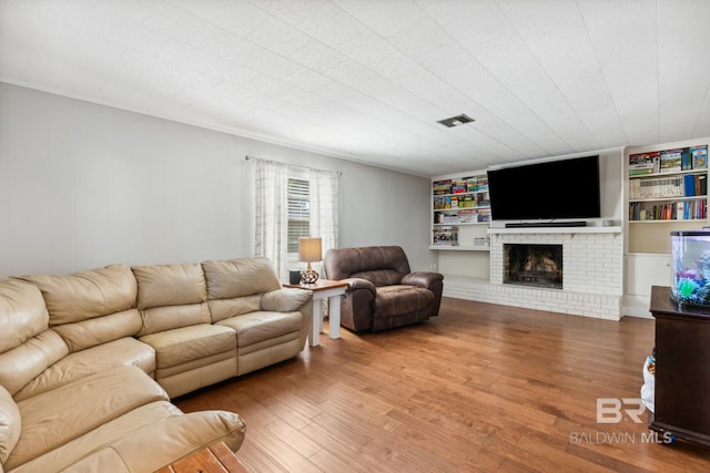 living room featuring hardwood / wood-style flooring and a brick fireplace