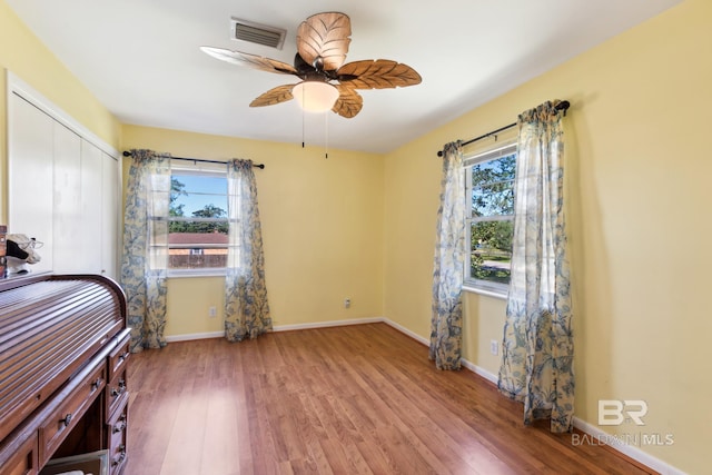 bedroom featuring a closet, wood finished floors, visible vents, and multiple windows
