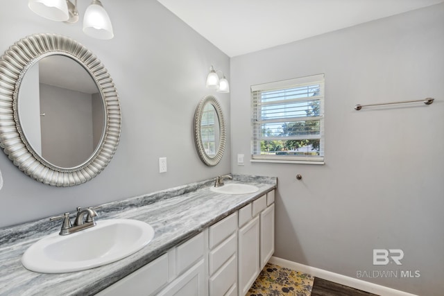 full bath featuring baseboards, a sink, and double vanity