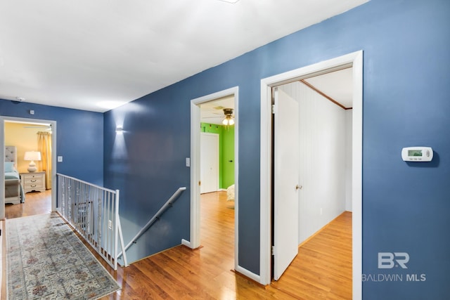 hallway with wood finished floors and an upstairs landing