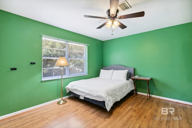 bedroom with ceiling fan, baseboards, and wood finished floors