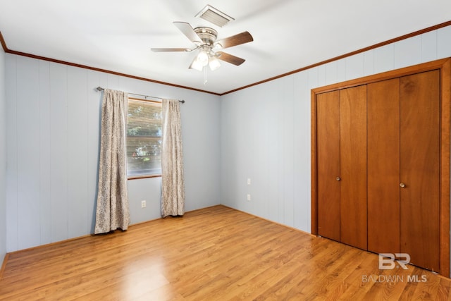unfurnished bedroom with crown molding, wood finished floors, visible vents, and a closet