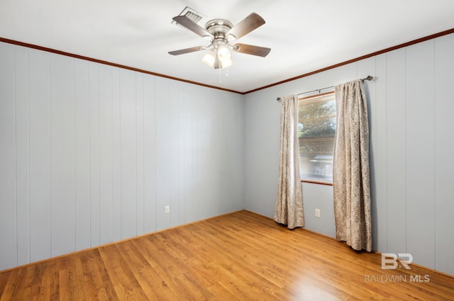 empty room with wood finished floors, a ceiling fan, and ornamental molding
