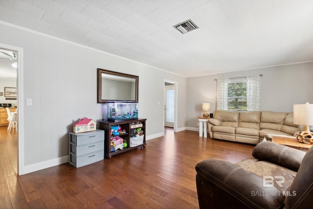 living room featuring baseboards, visible vents, dark wood finished floors, and crown molding