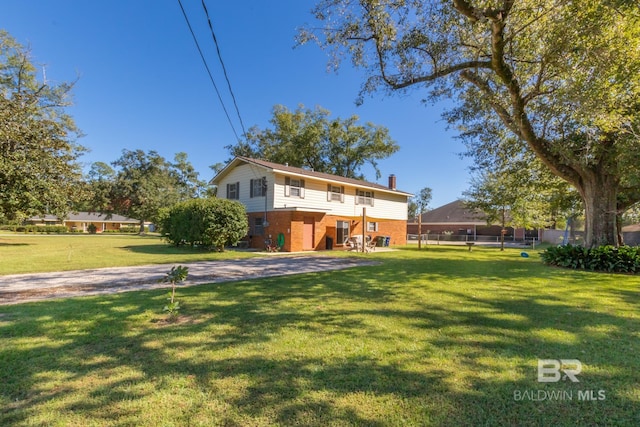 rear view of property featuring a chimney, brick siding, fence, and a yard