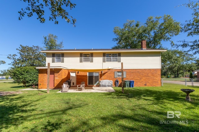 rear view of house with a lawn, a chimney, brick siding, and a patio