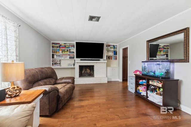 living room featuring built in features, wood finished floors, visible vents, and a fireplace