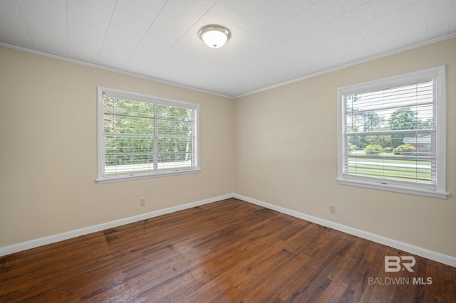 spare room with crown molding, dark wood-style flooring, and baseboards