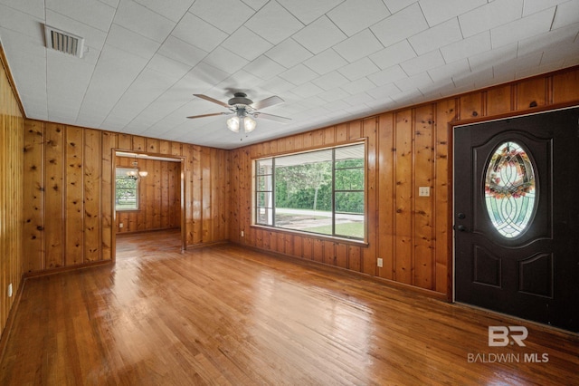 entrance foyer with plenty of natural light, a ceiling fan, light wood-style floors, and wood walls