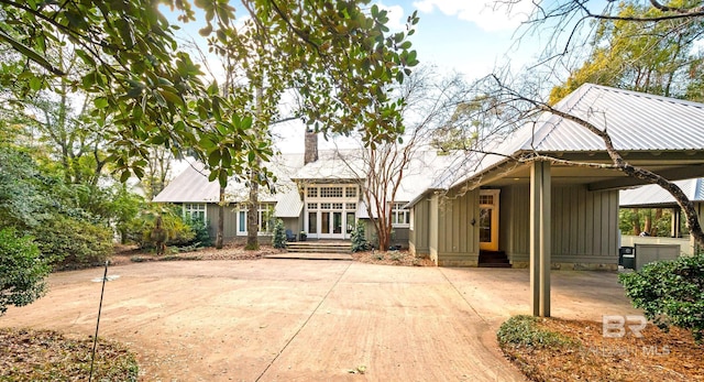 view of front of house with entry steps, metal roof, an attached carport, french doors, and board and batten siding