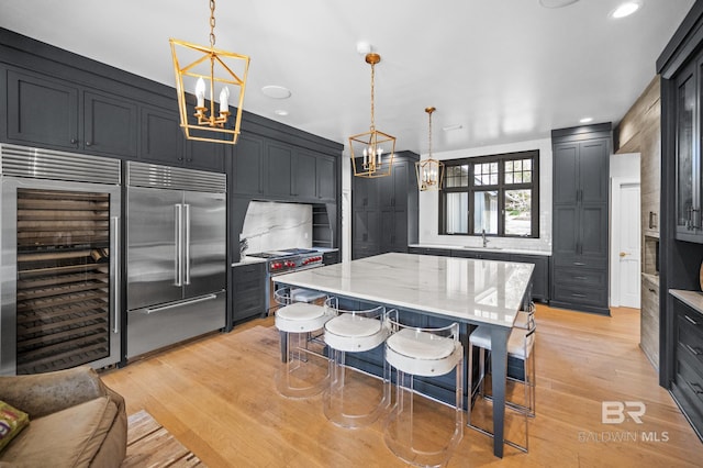 kitchen featuring hanging light fixtures, a breakfast bar, light stone counters, and high end appliances