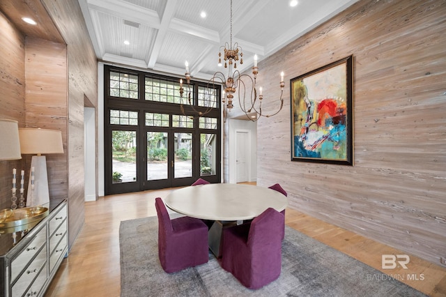 dining room with beam ceiling, coffered ceiling, a towering ceiling, and light wood-style flooring