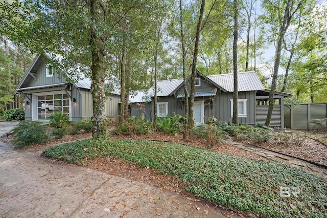 view of front of home featuring metal roof, board and batten siding, and fence