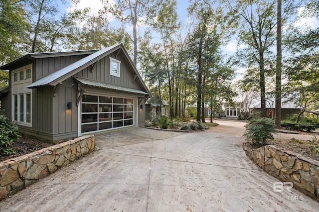 view of side of property with board and batten siding, driveway, and a garage