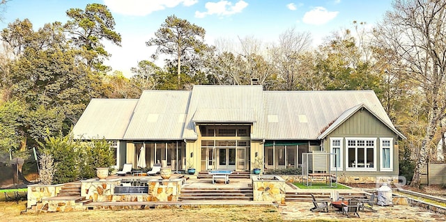 back of property featuring metal roof, an outdoor fire pit, a sunroom, a trampoline, and a chimney