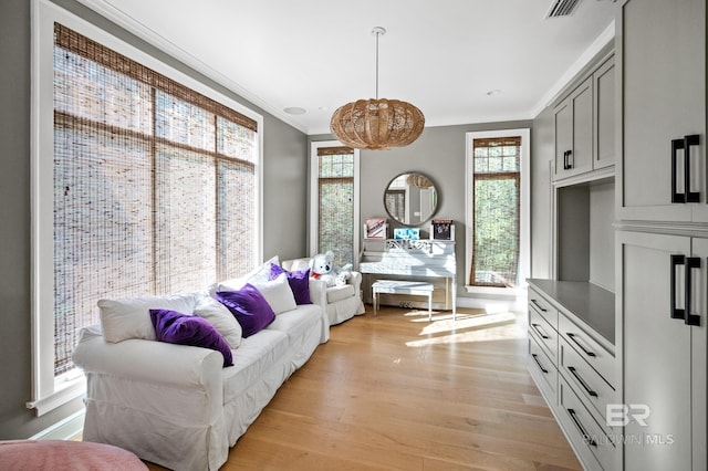 living area with light wood-type flooring, visible vents, and crown molding