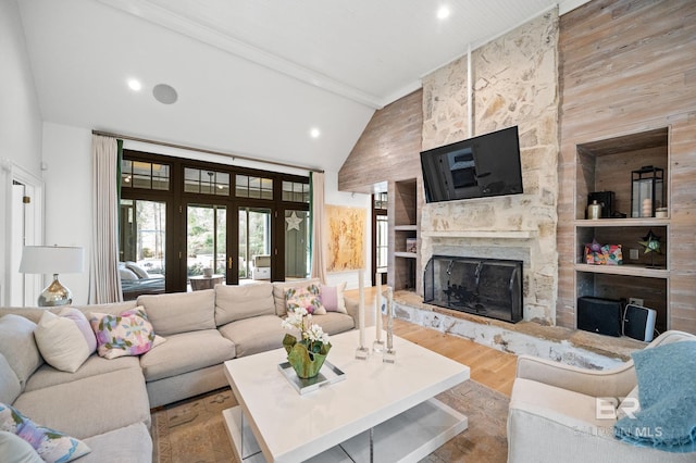 living room with light wood-style flooring, french doors, a fireplace, high vaulted ceiling, and recessed lighting