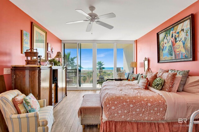 bedroom with a wall of windows, light hardwood / wood-style flooring, access to outside, and ceiling fan