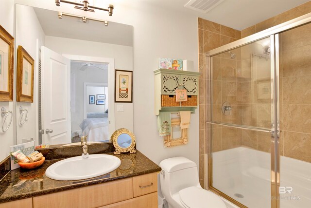 bathroom with toilet, an enclosed shower, vanity, and ceiling fan