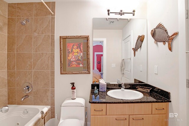 full bathroom featuring tiled shower / bath, vanity, and toilet