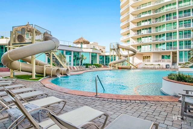 view of pool with a water slide, pool water feature, and a patio