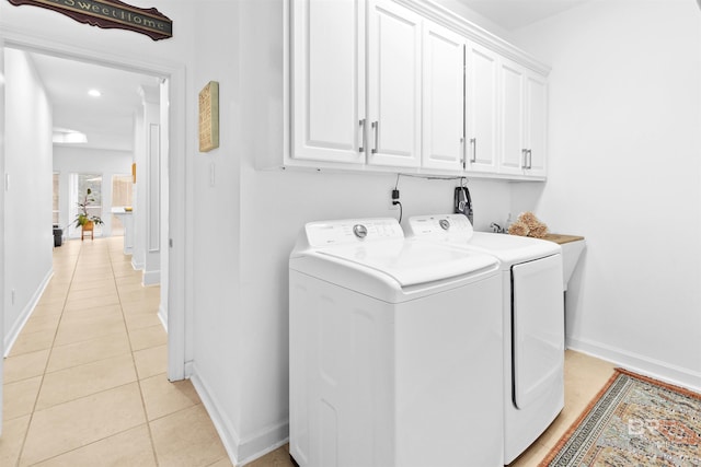 laundry area featuring light tile patterned floors, cabinet space, baseboards, and separate washer and dryer