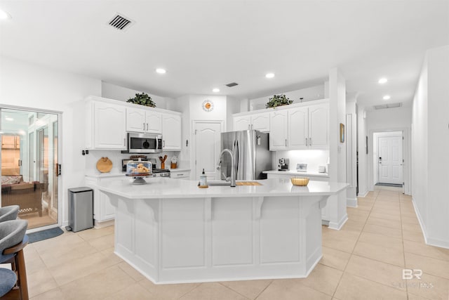 kitchen with light countertops, appliances with stainless steel finishes, visible vents, and white cabinets