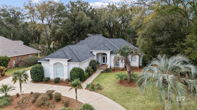 view of front of property with roof with shingles, a front yard, and stucco siding