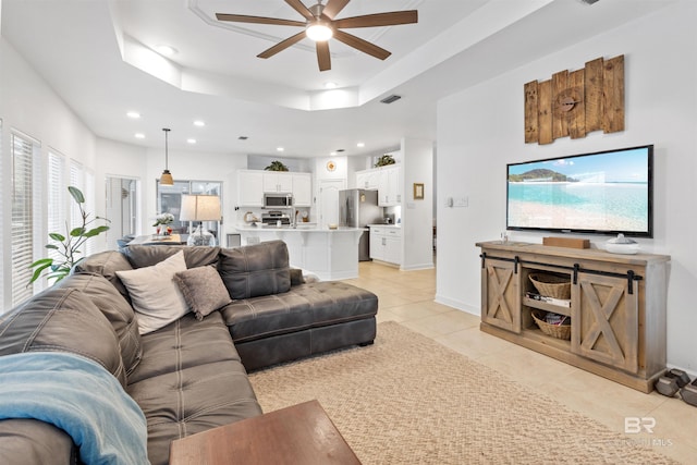 living room with light tile patterned floors, ceiling fan, recessed lighting, baseboards, and a raised ceiling