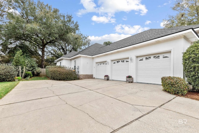 view of property exterior with driveway, roof with shingles, a garage, and stucco siding