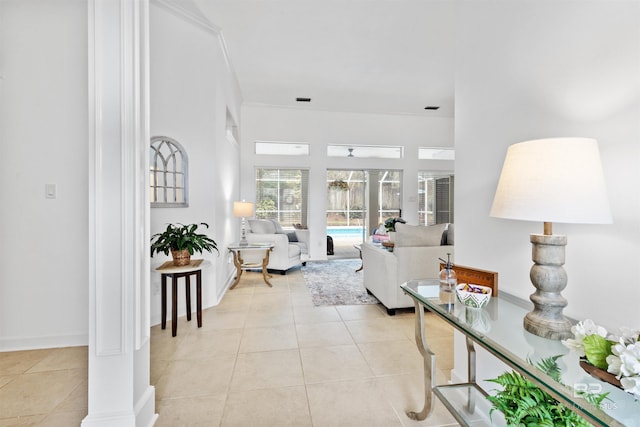 living area with light tile patterned floors, decorative columns, and baseboards