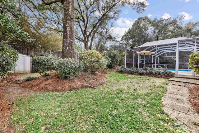 view of yard featuring a storage shed, an outdoor pool, glass enclosure, an outbuilding, and fence