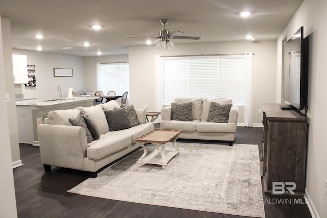 living room featuring dark hardwood / wood-style floors, ceiling fan, and sink