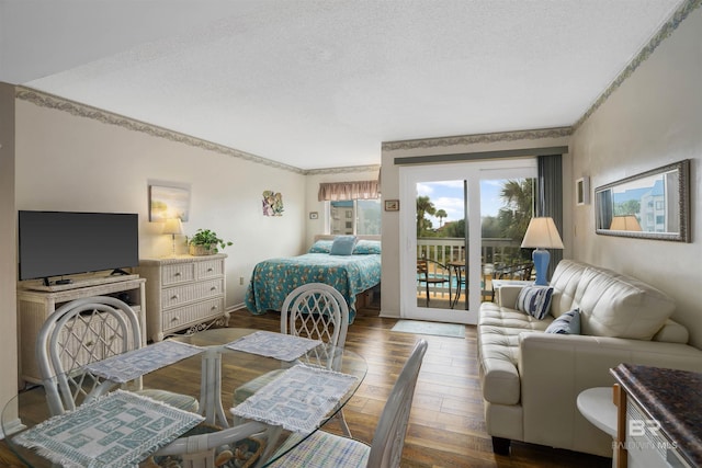 bedroom with access to exterior, hardwood / wood-style floors, and a textured ceiling