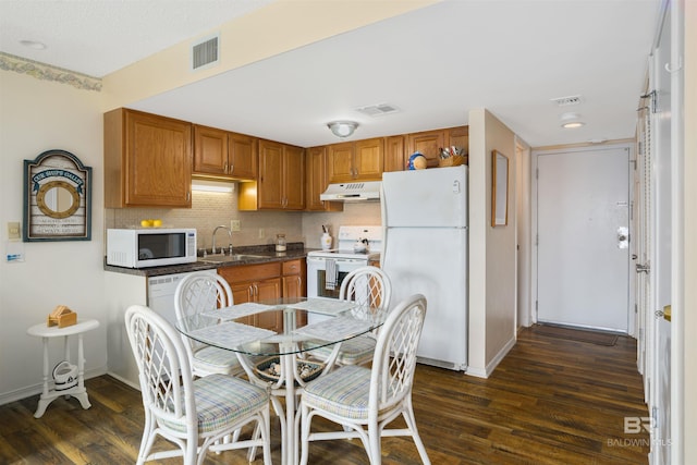 kitchen with backsplash, white appliances, sink, and dark wood-type flooring