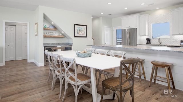 dining room with hardwood / wood-style floors, beverage cooler, and indoor wet bar