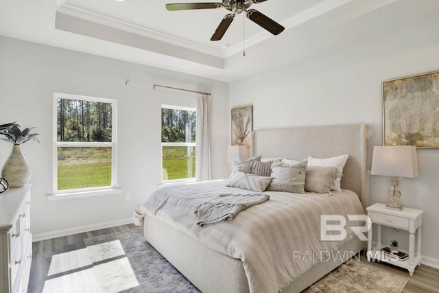 bedroom with a tray ceiling, ceiling fan, crown molding, and hardwood / wood-style flooring