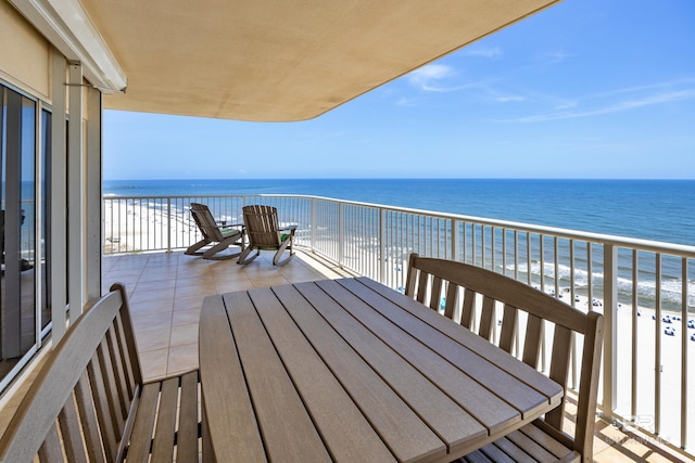 balcony featuring outdoor dining area and view of water and beach
