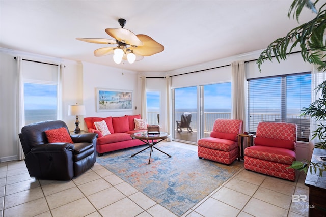 living room featuring light tile patterned flooring, a water view, and a ceiling fan