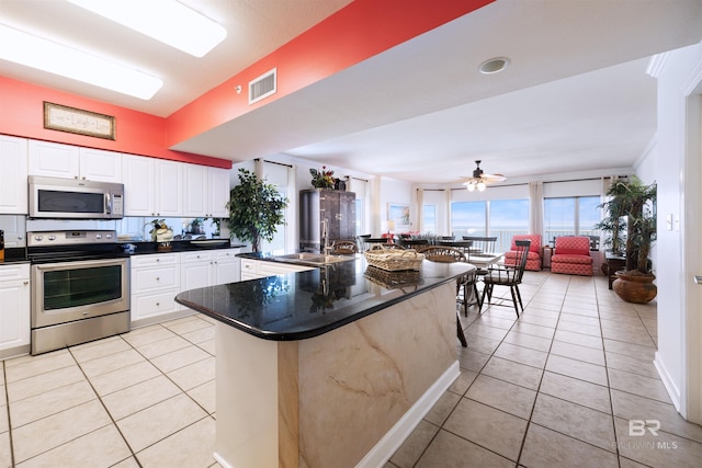 kitchen featuring appliances with stainless steel finishes, a sink, dark countertops, and light tile patterned flooring