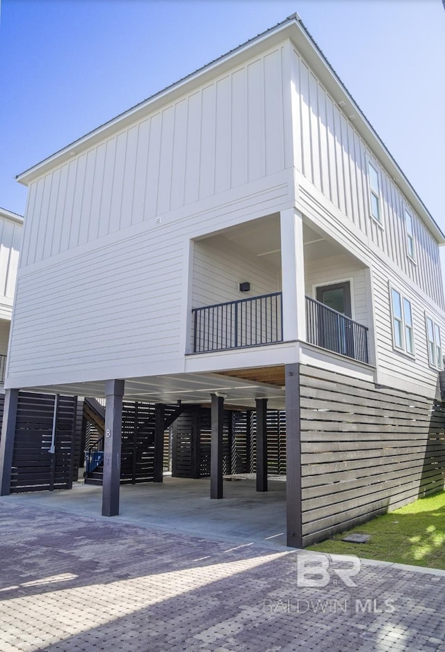 1476 Sandpiper Ln Unit B, Gulf Shores, AL 36542 - view of home's exterior featuring a carport, board and batten siding, stairway, and driveway