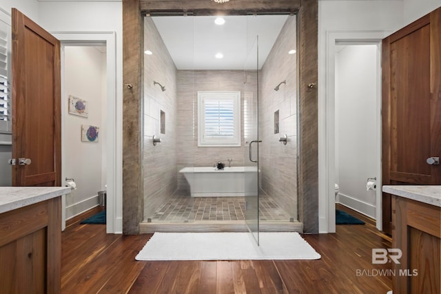 full bathroom with toilet, shower with separate bathtub, hardwood / wood-style floors, and vanity