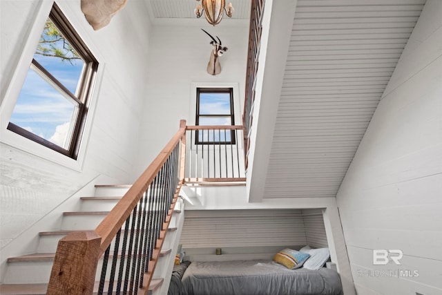 stairway with plenty of natural light, wooden walls, and vaulted ceiling