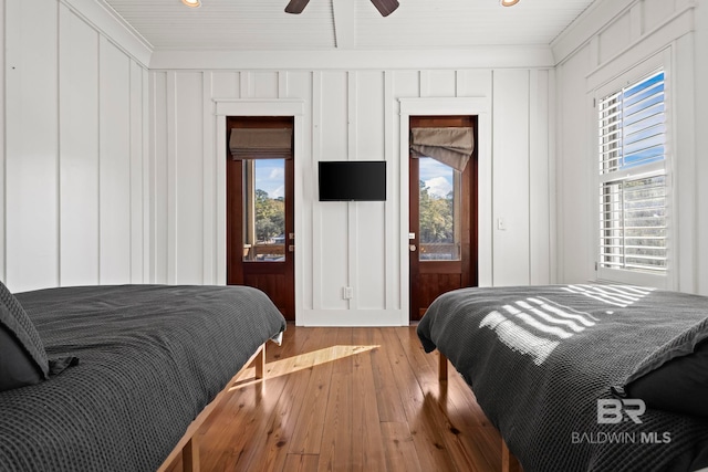 bedroom featuring ceiling fan, multiple windows, light hardwood / wood-style flooring, and crown molding