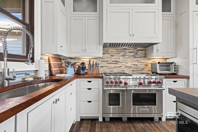 kitchen featuring double oven range, white cabinetry, and backsplash