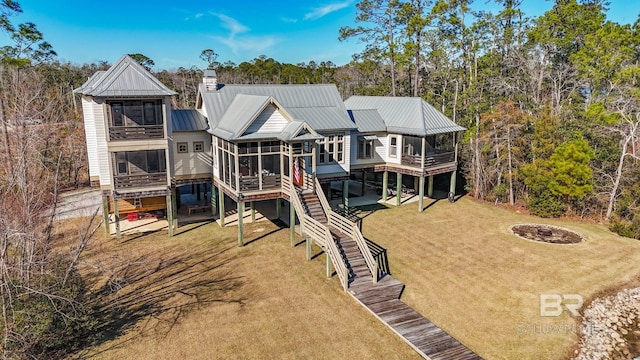 back of property with a lawn, a sunroom, a deck, and a fire pit