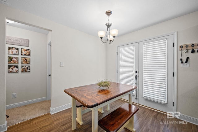 dining area with wood finished floors, baseboards, and a notable chandelier