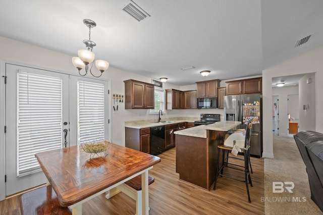 kitchen with light countertops, visible vents, a sink, and black appliances