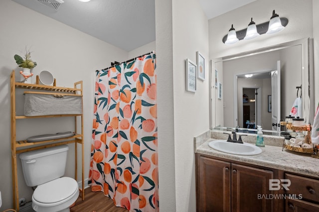 full bath featuring toilet, visible vents, wood finished floors, a shower with shower curtain, and vanity